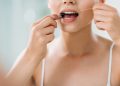cropped shot of young woman using dental floss in bathroom