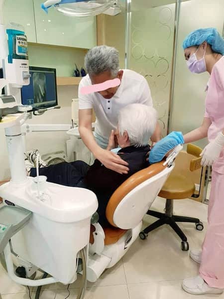 兒子將母親小心環抱到診療椅上