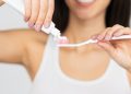 Unrecognizable Woman Putting Toothpaste On Toothbrush, White Background, Panorama